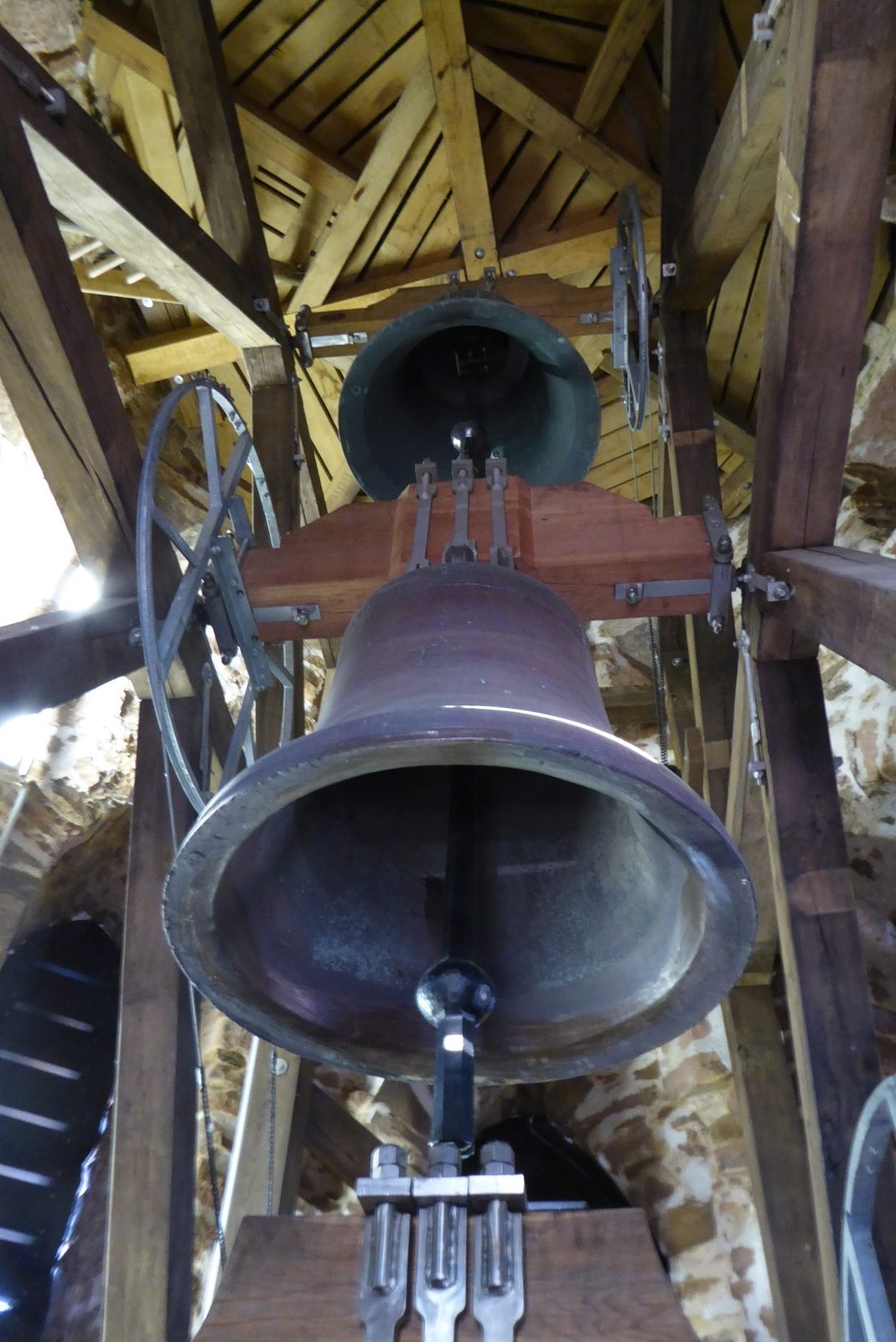 Blick in den Glockenstuhl des Buttermilchturms: zwei der drei Bronzeglocken hängen am hölzernen Joch unter dem offenen Dachgebälk.